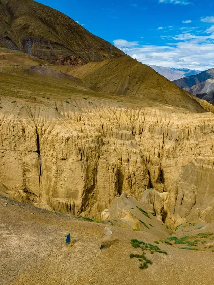 The surreal, eroded landscape of Lamayuru, often called the "Moonland" of Ladakh. The scale is hard to comprehend until you see the tiny figure of a person standing amidst the formations.