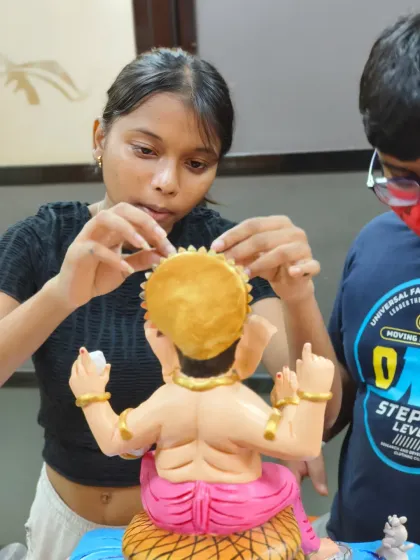 A close-up of the intricate work involved in creating a Ganpati idol. This student is carefully placing the finishing touches on the headpiece, demonstrating the patience and precision taught in our classes.