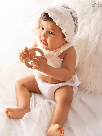 A sweet baby girl in a lace bonnet, curiously playing with a wooden teether. Simple props can keep little hands busy and lead to adorable, natural shots.