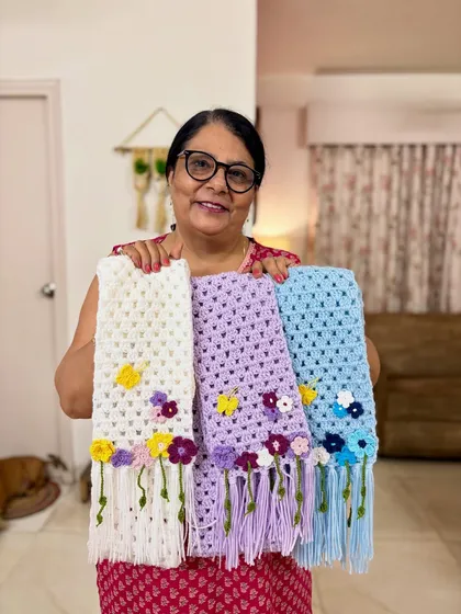 I love seeing my crochet flower scarves together. Each one, whether in white, lavender, or blue, is made with immense patience and attention to detail. The little flowers and tassels add a touch of handmade charm.