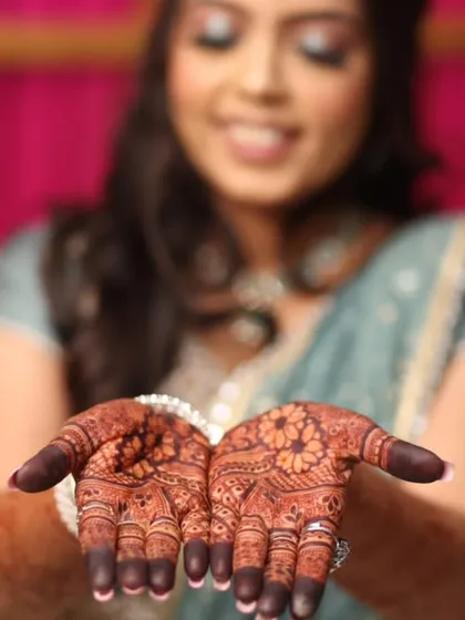 A happy bride showing off her engagement mehendi. The rich color looks stunning in professional photos.