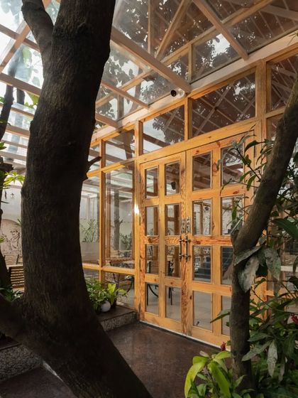 An exterior view of the main entrance, where the warm pine wood structure contrasts with the lush green landscape.
