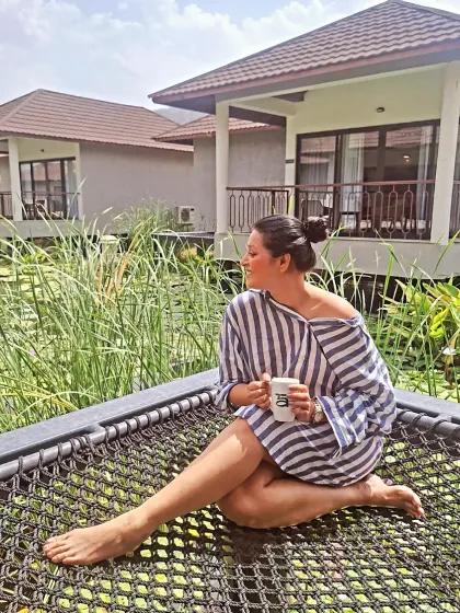 Serenity in every sunrise. Enjoying a cup of coffee on a hammock in a striped shirt dress, the perfect start to a peaceful day in Rajasthan.