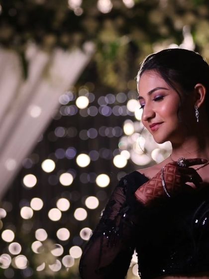 A dreamy, artistic shot with beautiful bokeh lights. The bride's elegant black gown and soft makeup create a truly magical reception look.