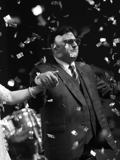 A black and white shot of a couple from the family dancing under confetti. We capture the magic of every performance.