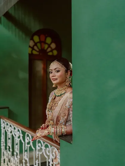 A bride looks out from a balcony, the green wall and white balustrade creating a beautiful colour contrast for this elegant shot.
