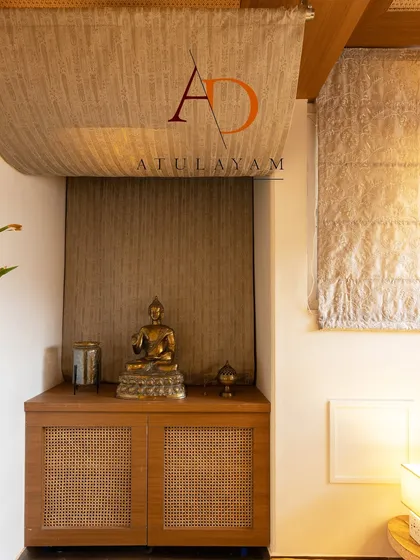 A corner of the meditation room, featuring a Buddha statue on a cane-front cabinet, with textured walls and fabric ceiling panels adding to the earthy, natural feel.