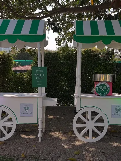 Adorable themed food carts, including a waffle cart and cotton candy station, designed with striped awnings to match the tennis club aesthetic.