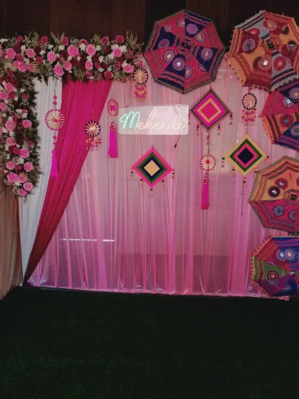 A wide shot of the pink Mehendi stage, showing the complete setup with the artificial grass flooring. This kind of decor works well in both indoor halls and outdoor spaces.
