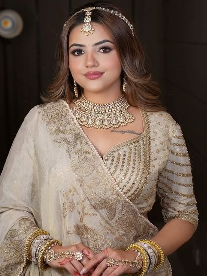 A close-up of the ivory and gold bridal look, focusing on the intricate choker, haath phool (hand harness), and matha patti.