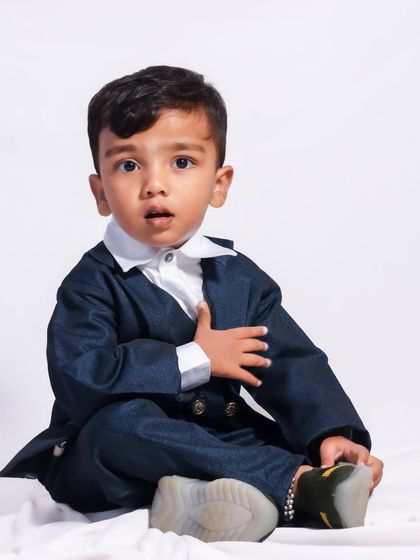 A candid moment during a studio shoot. This little boy, dressed in a smart suit, looks inquisitively at the camera, giving a natural and unposed feel to the portrait.