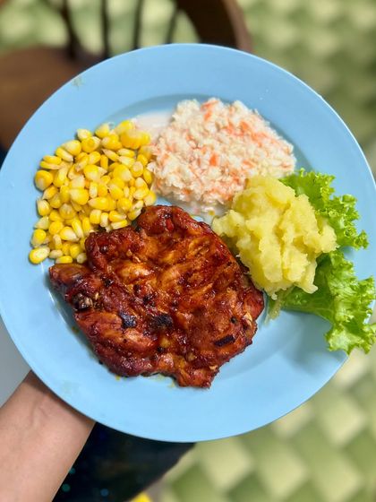 A continental-style high-protein meal with grilled chicken, mashed potatoes, steamed corn, and coleslaw. Healthy eating can be global!