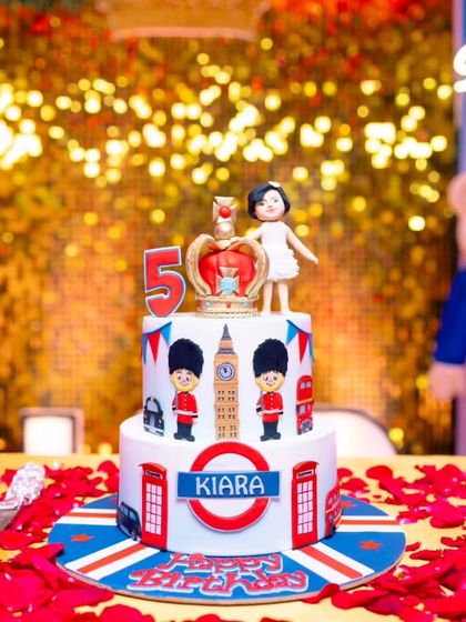 A two-tier London-themed cake for Kiara's 5th birthday, complete with the Queen's Guard, Big Ben, and a royal crown topper.