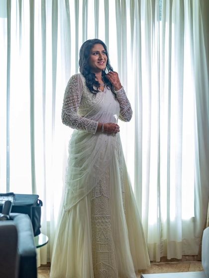 A full-length shot of the bride in her beautiful white lehenga-saree. The entire look is one of grace and modern elegance.