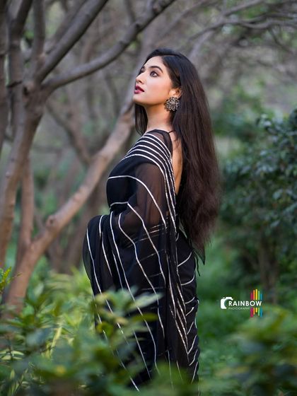 Actress Priyanka Thimmesh in a stylish black and white striped saree, shot in a wooded area. This blends traditional wear with a modern, moody aesthetic.
