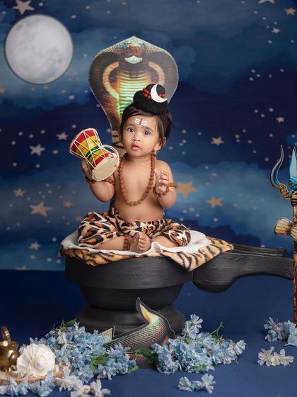 A tiny Lord Shiva holds his damaru, sitting peacefully in front of a starry night backdrop with the moon and a cobra.