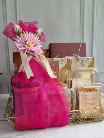 A vibrant pink hamper basket filled with our best-selling snacks like Sesame Crisps. We can customize colours and products to match your brand identity for bulk orders.