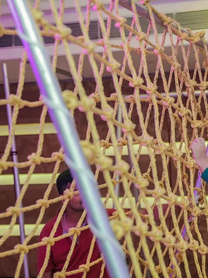 A young boy carefully navigates the rope climbing net. These activities are great for building confidence and coordination in a fun, supervised environment.