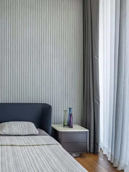 A detail shot of the minimalist master bedroom, showing the sleek vertical paneling and the sculptural pendant light that serves as a piece of functional art.
