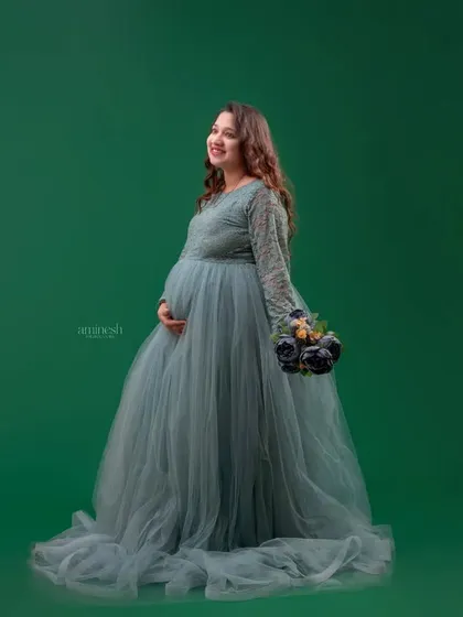 This dusty blue gown with detailed lacework on the sleeves offers a soft and romantic look. The solid green background makes the color of the dress pop, creating a beautiful contrast.