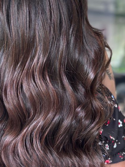 A detailed shot capturing the perfect curl pattern and the deep shine of this brunette hair color and style.
