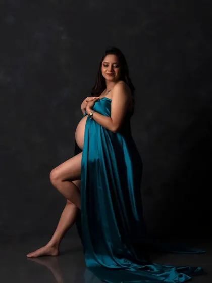 A powerful and artistic pose, highlighting the beautiful curves of pregnancy. The flowing fabric adds a dynamic and elegant element.