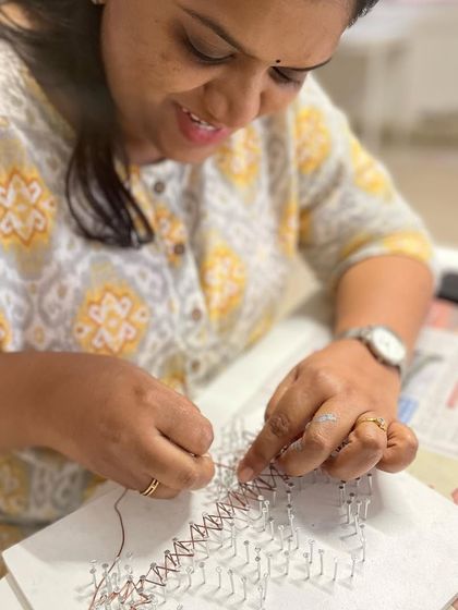 A smile of satisfaction as this artist works on her string art, enjoying a moment of creative escape.