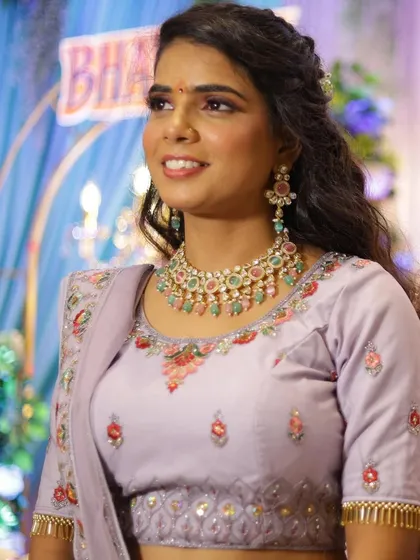 This bride chose a stunning lavender lehenga for her engagement. The makeup features complementary pink and lavender tones on the eyes and a natural base, paired with wavy curls.