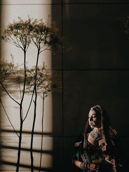 An artistic portrait of Sharun, with shadows of trees creating a beautiful pattern on the wall behind her. This shot is a perfect example of how we use natural elements to create unique and compelling images.