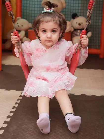 A sweet toddler enjoying a gentle swing in our dedicated younger kids' area. The soft flooring and age-appropriate equipment ensure a safe experience for our littlest guests.
