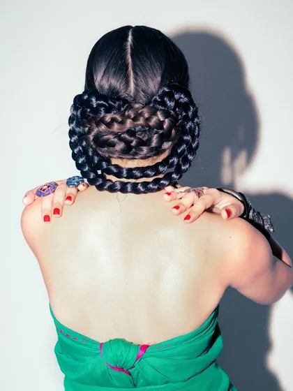 The back view of the green saree look, showcasing an intricate braided hairstyle that adds a structural element.