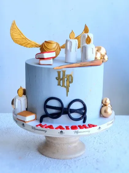 A clean shot of the Harry Potter cake, focusing on the toppers like the Golden Snitch and magic wand.