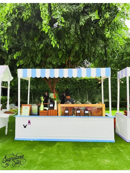 A classic food stall with a blue and white striped awning, serving treats at the Disneyland party. Even the functional elements are designed to fit the cheerful, park-like theme.