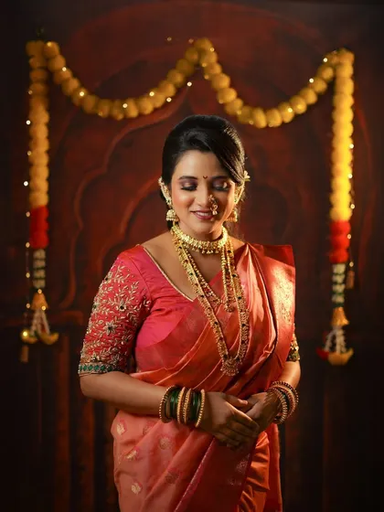 A serene portrait of a woman in her festive Diwali attire, standing gracefully in front of a traditionally decorated door.