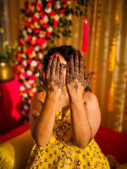 A playful peek-a-boo pose with minimalist henna, showing the delicate patterns on the back of the hands.