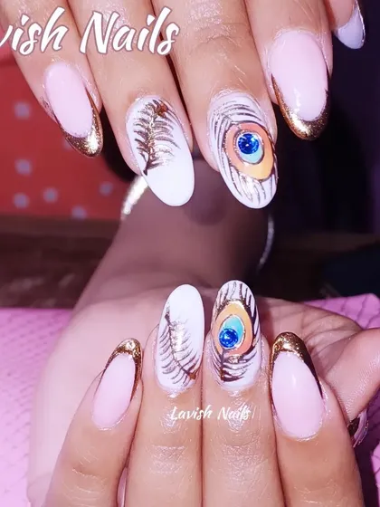Showcasing high-level artistry, this custom nail set includes hand-painted peacock feathers with a central blue gem, paired with a modern gold-tipped French manicure.