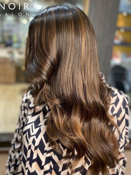 A "Wow Wednesday" hair color. This look features a beautiful blend of chocolate and caramel tones, styled in soft waves for a sophisticated finish.