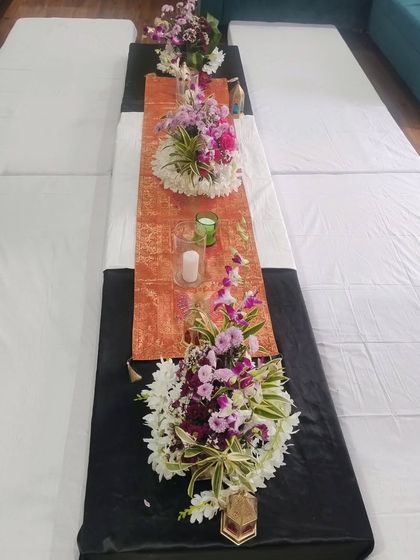 An elegant table runner arrangement with fresh flowers and candles for a formal dinner or event.