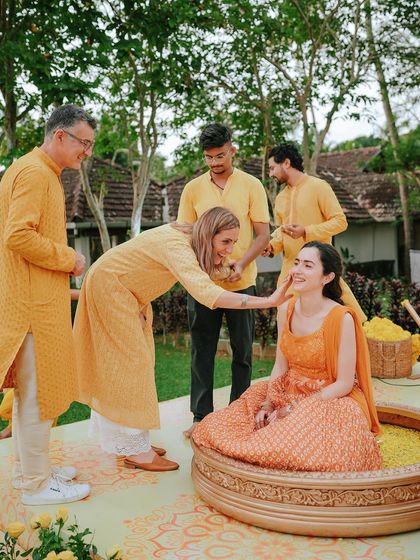Family members lovingly applying Haldi to the bride. These traditions are all about community and blessings, and I make sure to capture those connections.