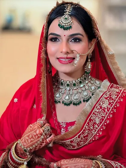 This bride radiates happiness. Her makeup is fresh and natural, with a simple bindi, a classic nose ring, and henna-adorned hands completing her traditional look.
