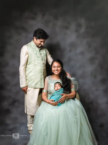 A formal family portrait celebrating the arrival of a new baby. The parents are dressed elegantly, creating a timeless and celebratory image that marks this significant family milestone.