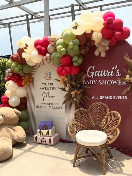 The main backdrop for the baby shower, featuring a wicker peacock chair for the mom-to-be and props like a teddy bear aviator.