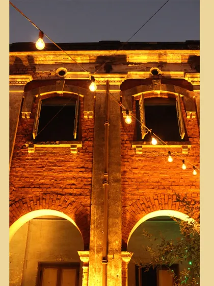 Simple string lights illuminating the brick facade of a heritage building at night, a low-cost, high-impact way to create atmosphere and highlight architectural details.