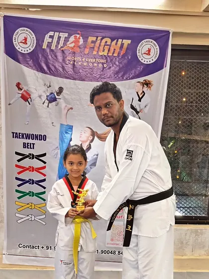 A young yellow belt student receives a trophy from our chief guest, Junaid sir, during our belt promotion ceremony.