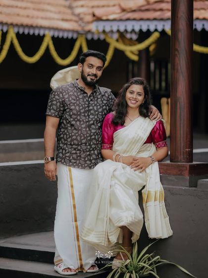 A classic portrait of the couple in traditional Kerala wear, posing in a beautiful, rustic setting.