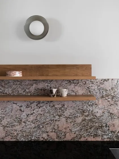 A detail shot from a kitchen, showing the material mix of a pink granite backsplash and oak shelving. I enjoy combining different natural materials to create a rich, tactile, and colorful palette.