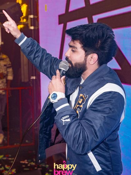 On the mic at Happy Brew, pointing to the sky and getting the crowd hyped.