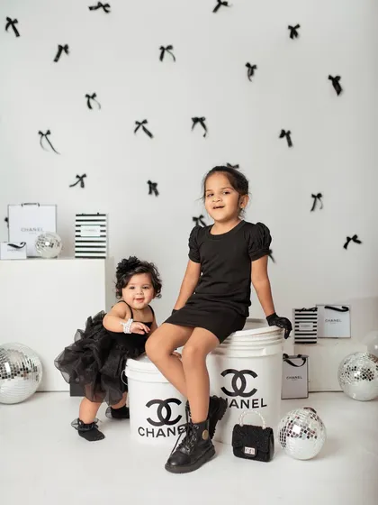 Partners in crime and style. The two sisters pose together, showing off their coordinated black outfits and the fun, fashion-themed props.