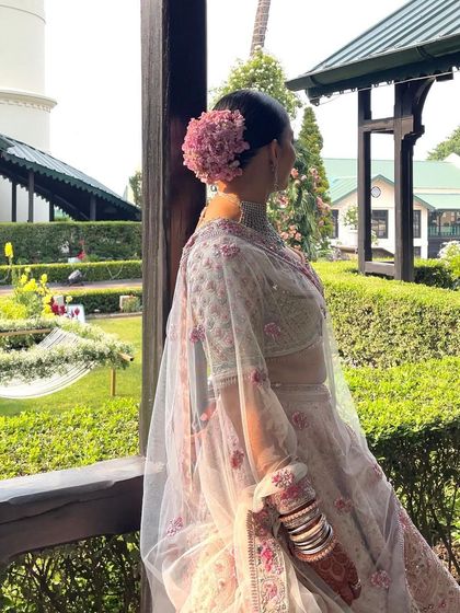A side view of the bride looking out from a balcony. The floral bun adds an element of elegance to her profile.