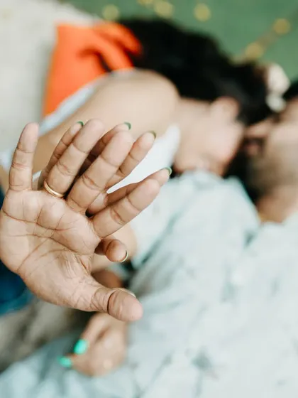 An artistic, shallow-depth-of-field shot focusing on the couple's hands and engagement rings as they lie together.